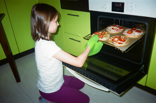 Daughter taking pizza out of the oven.