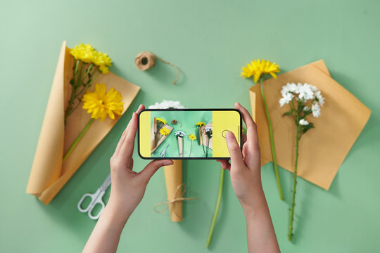 Hands taking mobile photo of fresh flowers