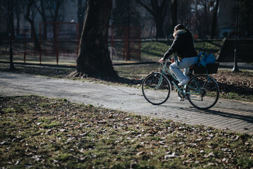 Fototapeta premium Casual cyclist riding a bicycle through a tranquil park on a sunny day.
