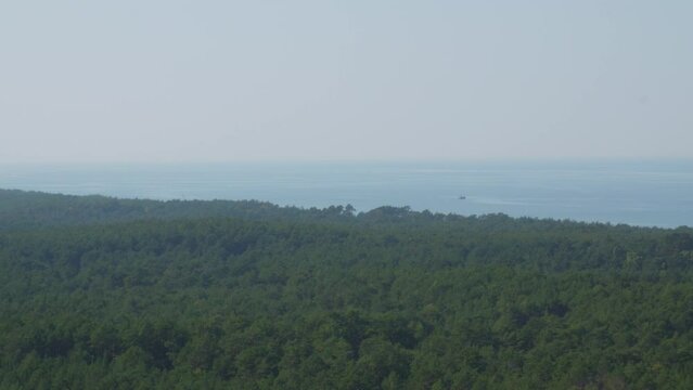 A panoramic view from the top of the Stilo lighthouse, overlooking the lush green forest and the Baltic sea. Static shot.