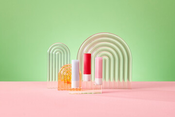 Decorative acrylic podiums and lipstick on green background