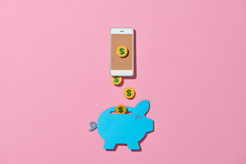Gold money coins flying out of the smartphone into piggy bank