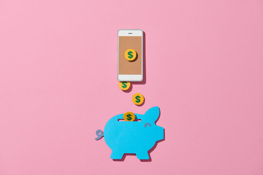 Gold money coins flying out of the smartphone into piggy bank