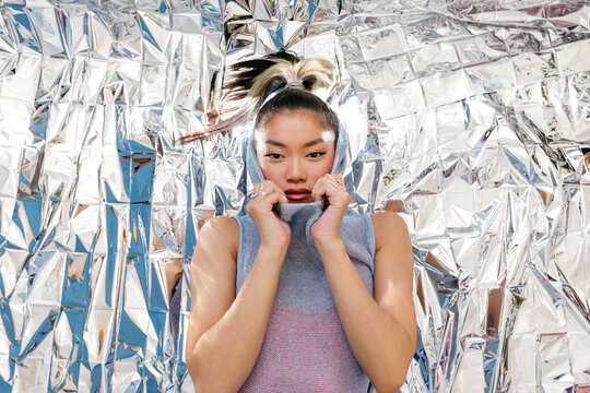 Serious young woman lying on foil surface