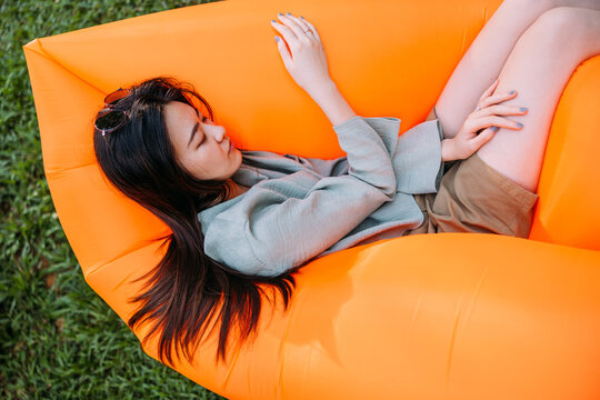young woman resting on an air sofa in the park