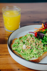 A plate of avocado toast with a glass of orange juice
