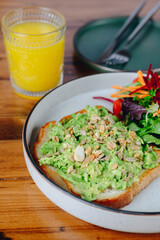A plate of avocado toast with a side of vegetables and a glass of orange juice