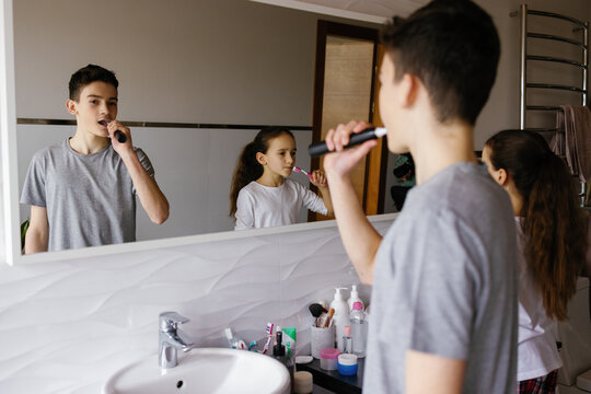 Siblings doing morning procedure shared bathroom brushing teeth