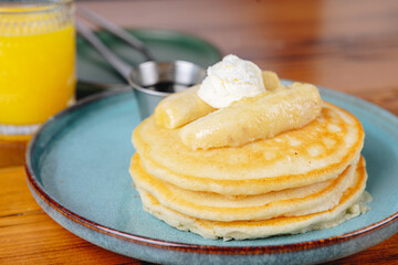 A stack of pancakes with bananas on top of them is served on a blue plate