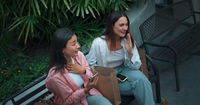 Young women sits on bench with phones sharing moments laughter top view. Laughter reflects bond joy friendship Laughter sign women's friendship respect positive vibes Embracing life's joys.