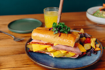 A sandwich with ham, cheese, and vegetables is on a blue plate