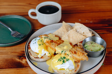 A plate of breakfast food with a side of chips and guacamole