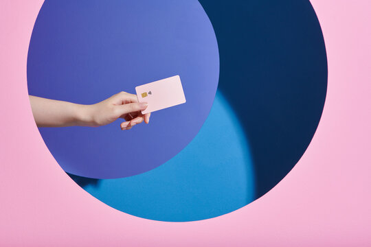 Woman hand holding credit card on blue and pink background