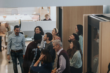 Diverse team of professionals sharing a light-hearted moment in a modern office. Candid scene...
