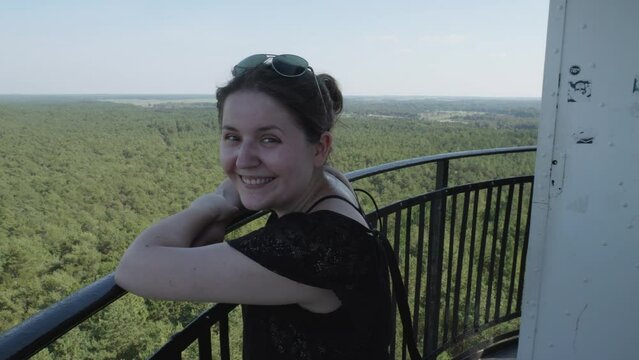 A woman admires the panoramic view of the lush green forest and the sea from the top of the Stilo lighthouse in Stilo, Poland.