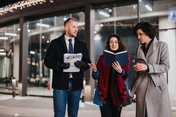 Young business colleagues in winter attire discussing documents at evening.