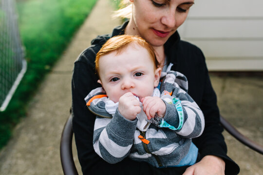 Mother holds red headed baby on her lap