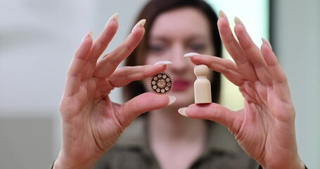 Business woman holding gear and a wooden figure