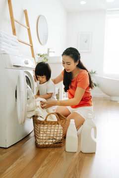 Mother with daughter sorting clothes after laundry
