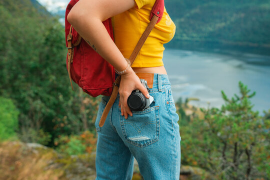Woman taking camera from rear pocket of the jeans to take a picture