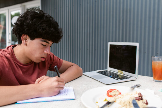 Teenager boy doing homework in cafeteria  