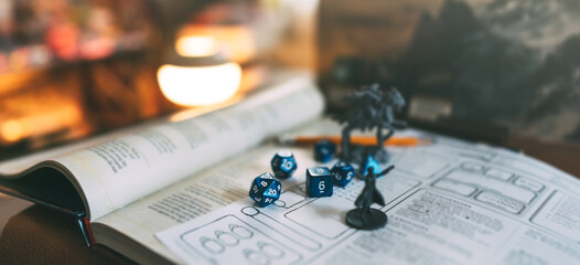 Miniatures and blue dice place on adventure story TTRPG book role playing tabletop game and board...