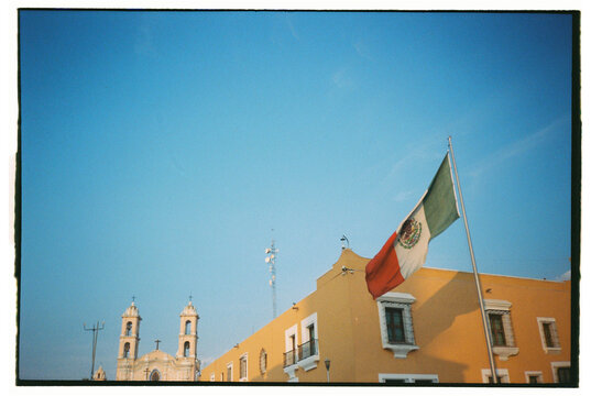 Corner of yellow building and church with Mexican flag