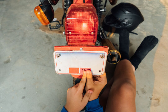 Hand pushing a license plate tag onto moped. 