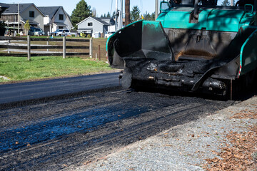 Road repaving project in progress, half the street repaved with fresh asphalt and half ready for...