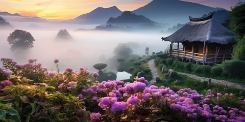 Fotobehang Magical scene of a thatched cottage amid blooming flowers with a mist-covered mountain landscape © Coosh448