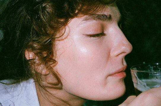 Curly hair woman smelling and tasting her beer with eyes closed 