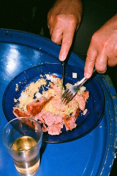 Man enjoying Brazilian sausage barbecue and farofa and drinking beer