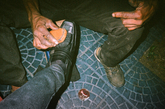 Vintage analog picture of shoe shiner working on man's leather shoes