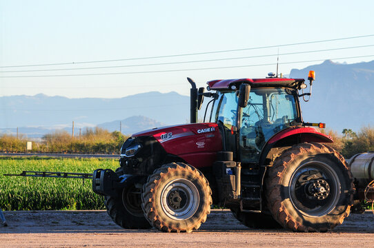 A crop tractor for plowing and harrowing agricultural fields parked adjacent to a field crop in Pinal County, Arizona