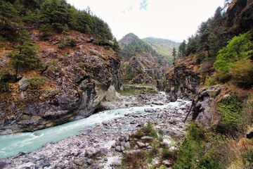 Fast moving rapids of the Dudh Kosi river originating from the Khumbu and Cho Oyu glaciers seen here in a scenic valley setting on the Everest Base Camp trek in lower Namche Bazaar,Nepal - obrazy, fototapety, plakaty