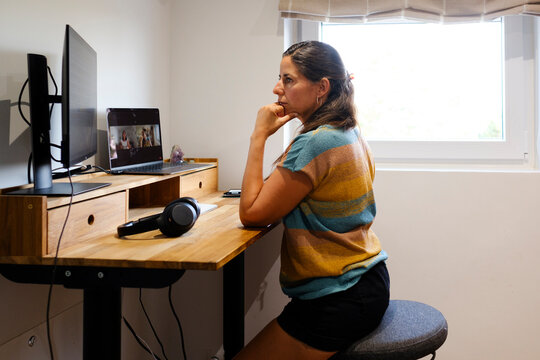 Woman sitting on stool working in standing desk in home office