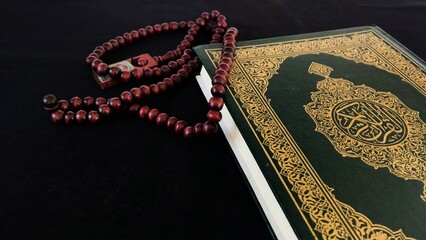 The Koran or Al-Qur'an, the holy book of Islam and prayer beads are placed on a black background