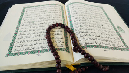 an open Koran or Al Quran and prayer beads on it. Islamic holy book