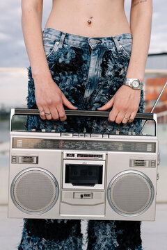 Crop woman listening to music on vintage cassette record player