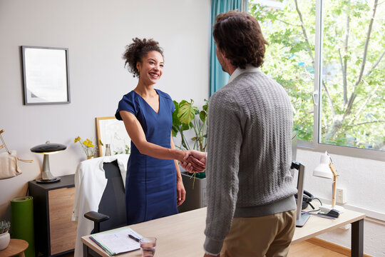 Happy business partners shaking hands in office