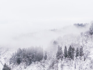 Fototapeta na wymiar ドローン写真：霧が立ち込める、綺麗な雪に覆われた雪山