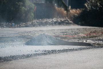 Pile of hot asphalt at end of section of freshly paved road, road construction in progress
