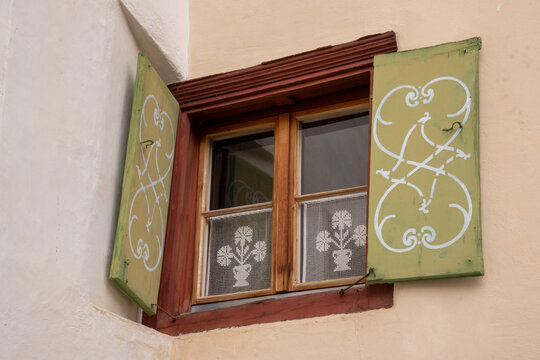 Window decorated with flowers with wooden frames and decorative shutters on a typical, traditional Engadine house in Switzerland