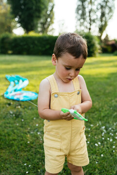 Little boy playing with kite string handle in garden