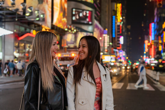Two Happy Girls Walking In New York At Night.