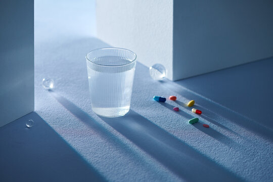 vertical image of glass with water and pill capsules