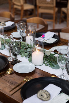 A candle inside a glass vase on a table at a wedding