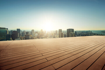 Empty wooden floor in front of.city view background during sunrise.