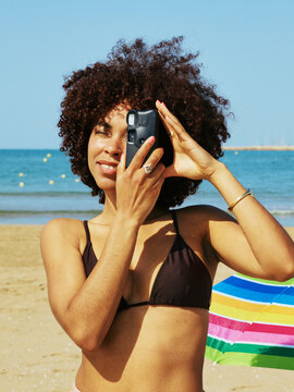 Woman using vintage analog camera to take picture at sunny beach