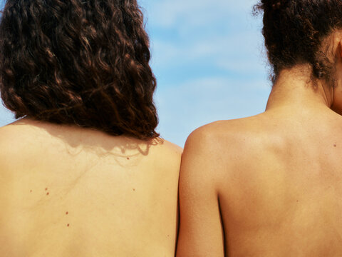 Two anonymous woman sunbathing topless at the beach